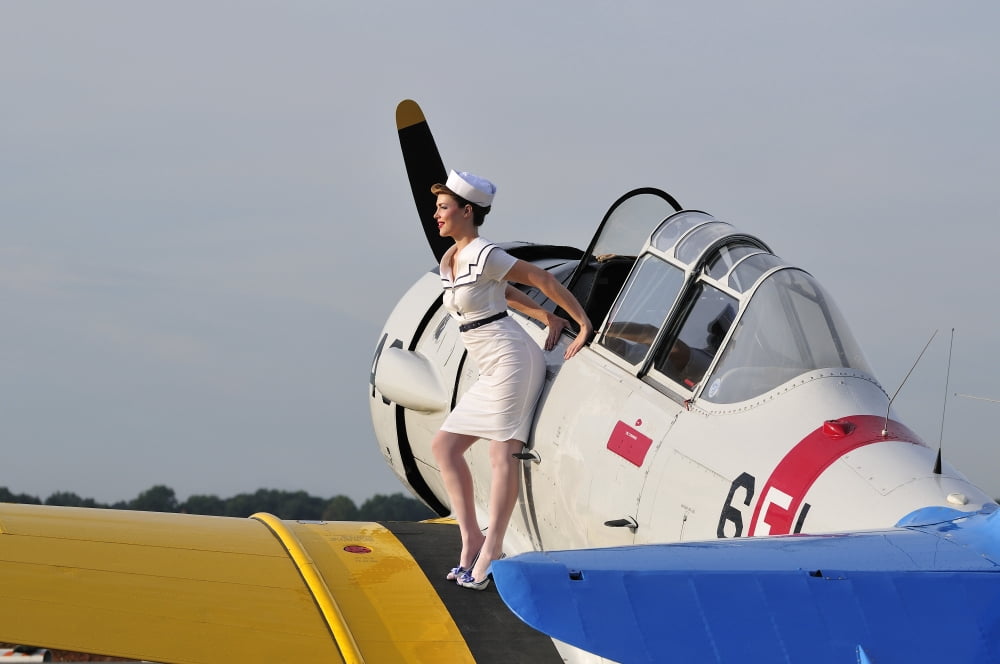 1940s style pin-up girl sitting on the wing of a vintage T-6 Texan aircraft Canvas Art - Christian KiefferStocktrek Images (18 x 12)