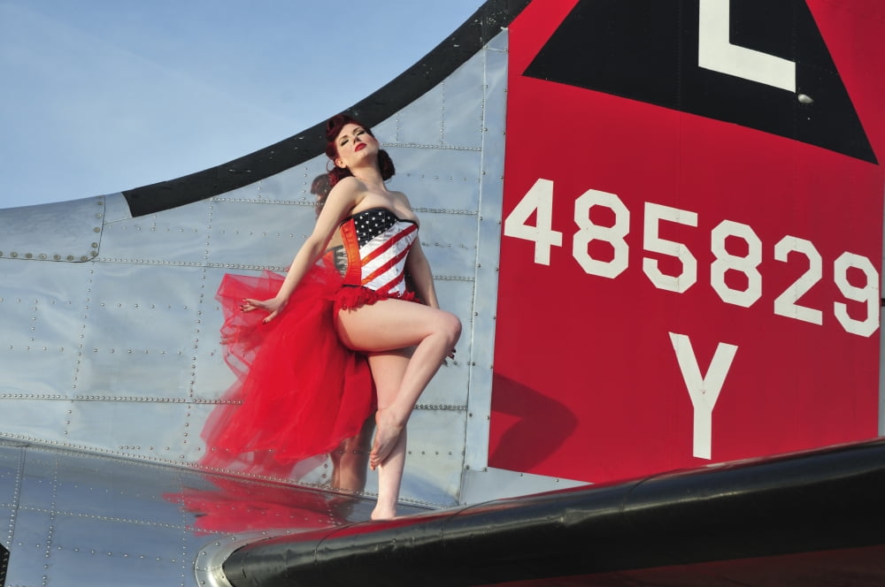1940s style pin-up girl standing on the tail of a B-17 bomber Canvas Art - Christian KiefferStocktrek Images (18 x 12)