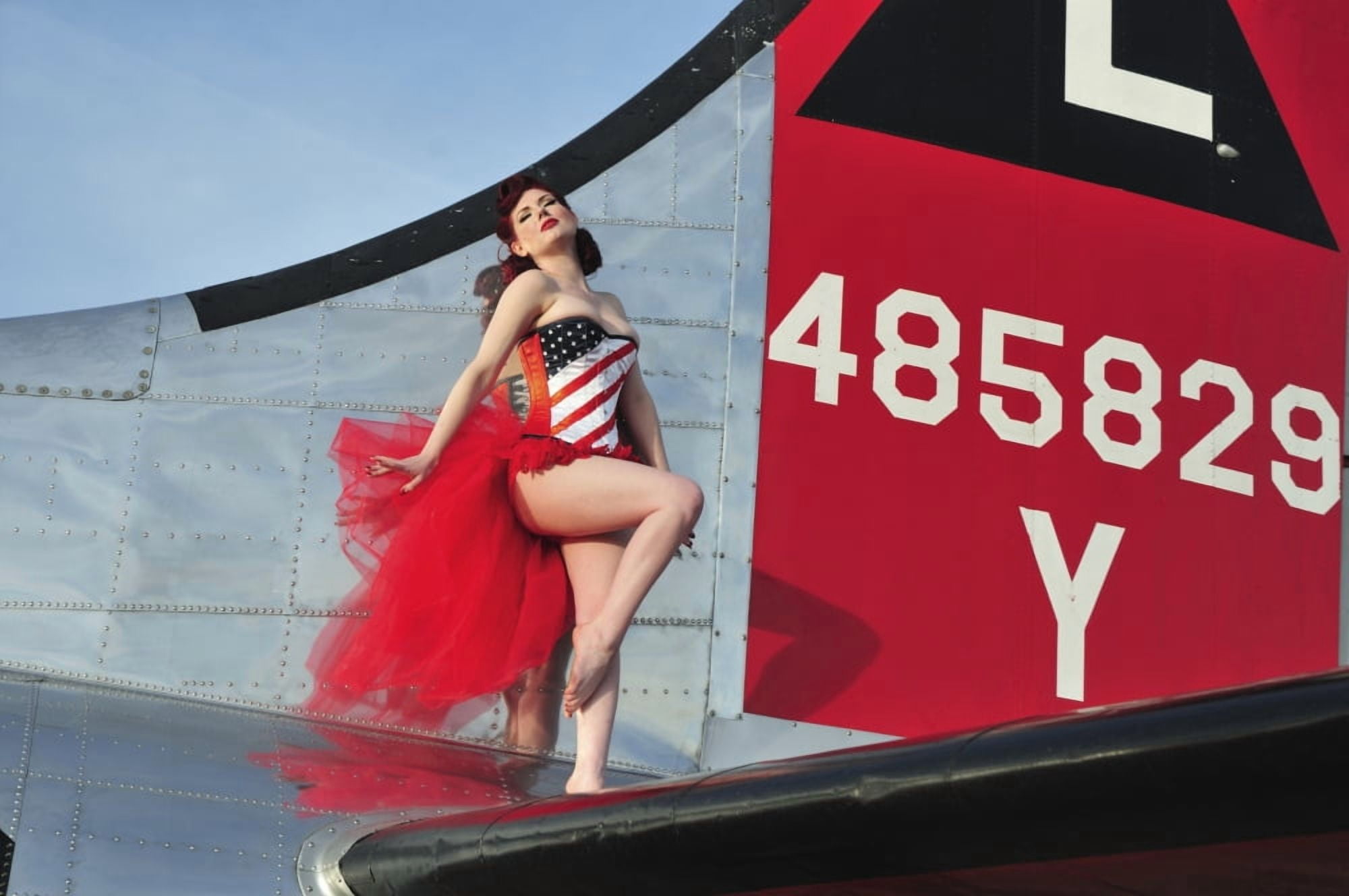 1940s style pin-up girl standing on the tail of a B-17 bomber Canvas Art - Christian KiefferStocktrek Images (35 x 23)