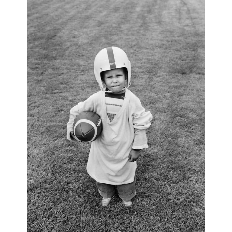 1950s Boy Standing In Grass Wearing Oversized Jersey And Helmet