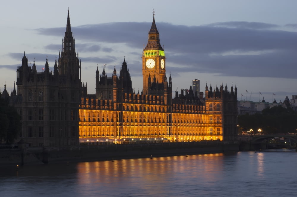 A Building And Clock Tower Along The Waters Edge Illuminated At Dusk London England Canvas Art - Charles Bowman Design Pics (38 x 24)