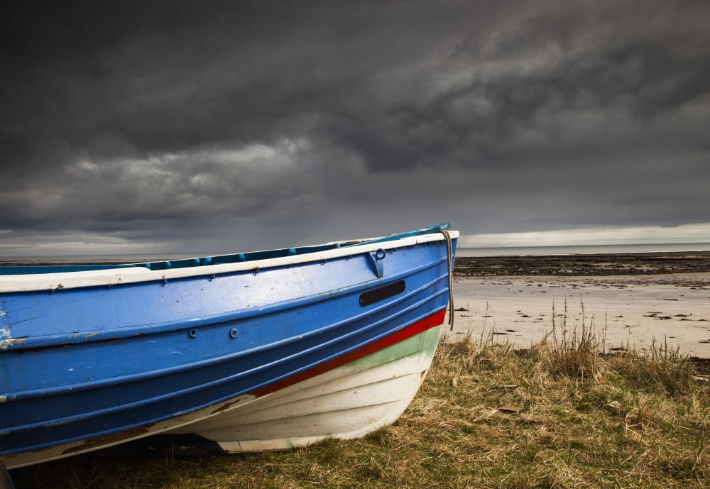 A Colourful Rowboat On The Shore With Dark Storm Clouds Overhead Boulmer Northumberland England Canvas Art - John Short Design Pics (36 x 24)