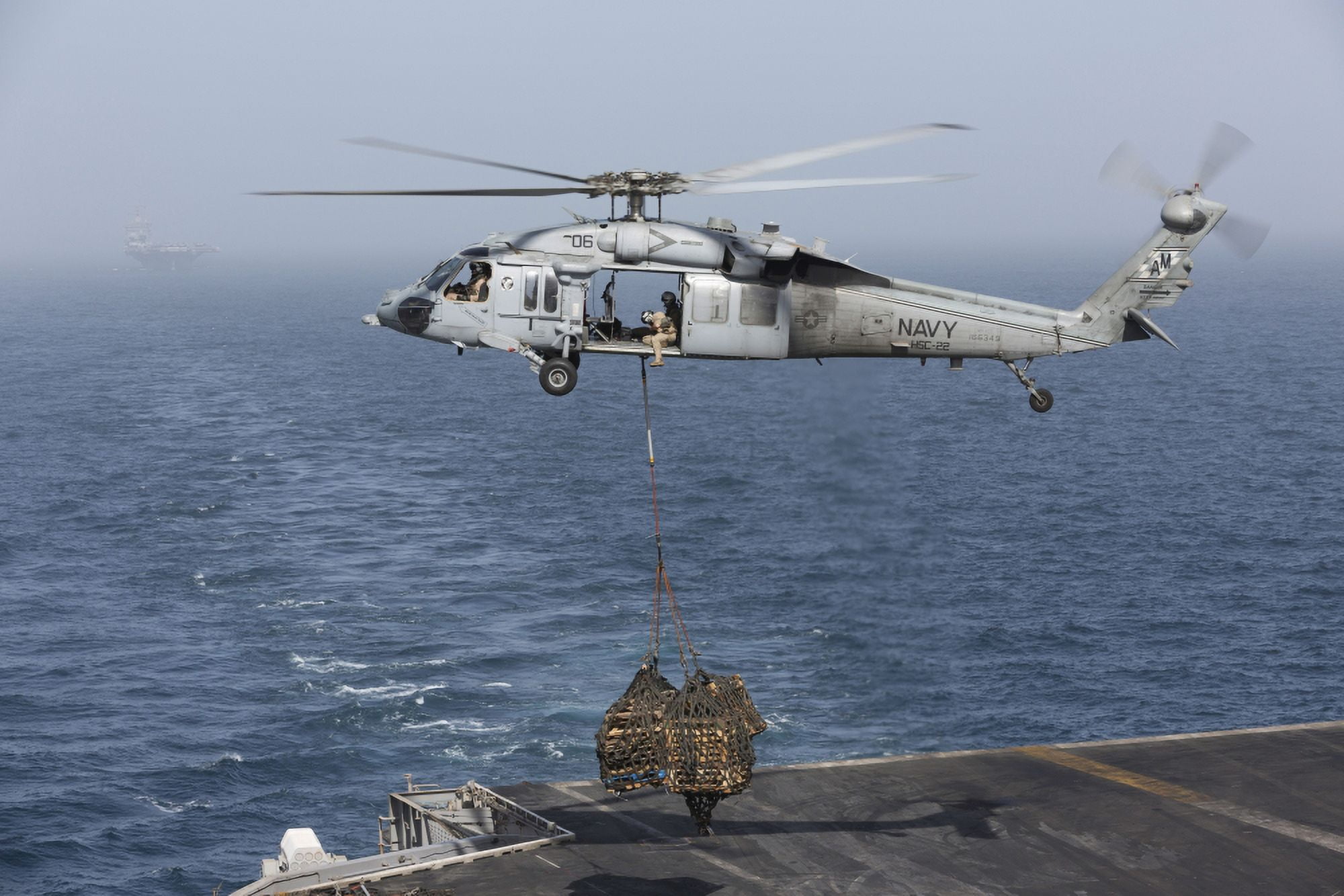 A MH-60S Knighthawk conducts a vertical replenishment at sea Canvas Art - Gert KromhoutStocktrek Images (35 x 23)