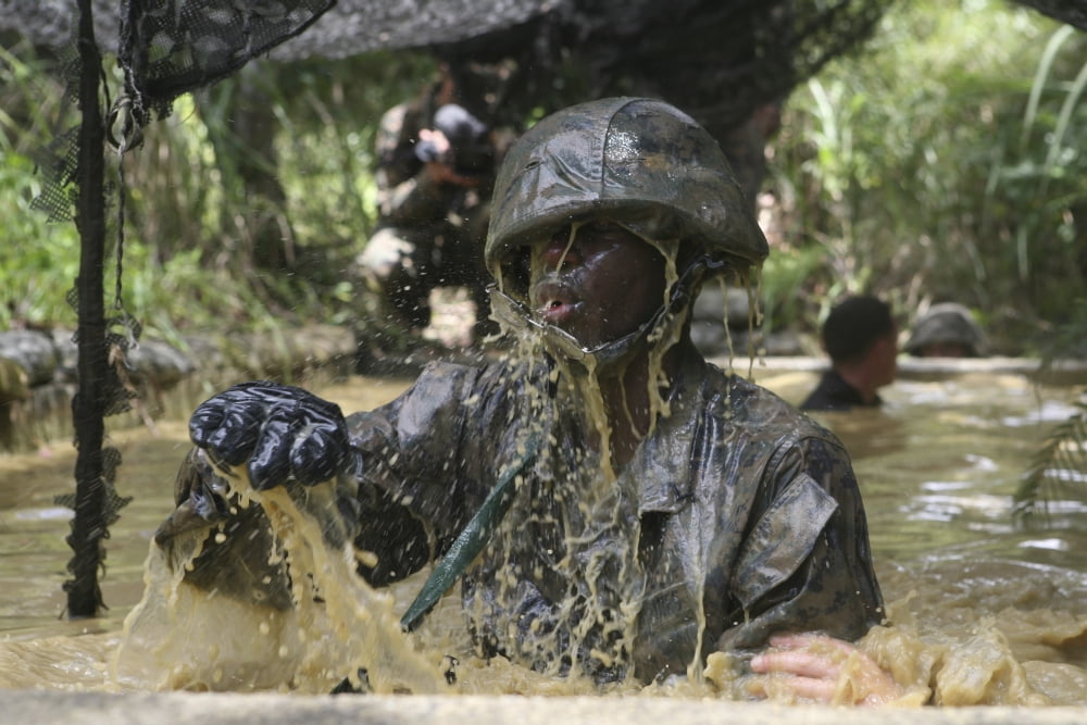A Marine splashes as he makes his way through an obstacle course at the Jungle Warfare Training Center Canvas Art - Stocktrek Images (34 x 23)