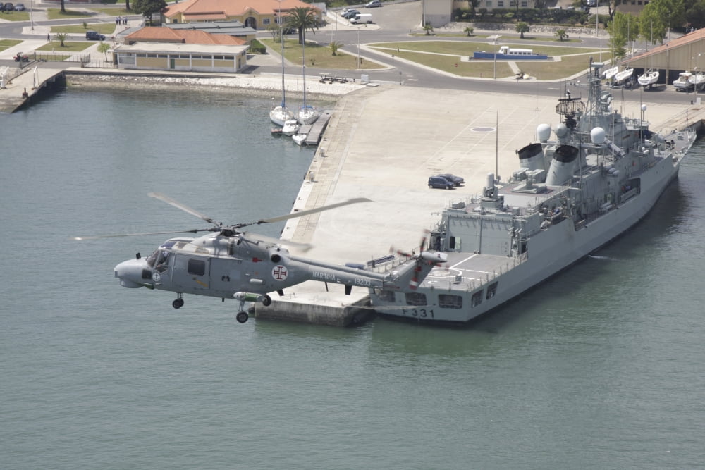 A Portuguese Navy Lynx helicopter flying over the harbor Canvas Art - Timm ZiegenthalerStocktrek Images (18 x 12)