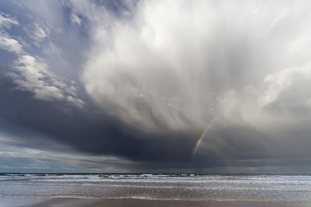 A Rainbow In The Dark Clouds Over The Ocean Bamburgh England Canvas Art - John Short Design Pics (19 x 12)