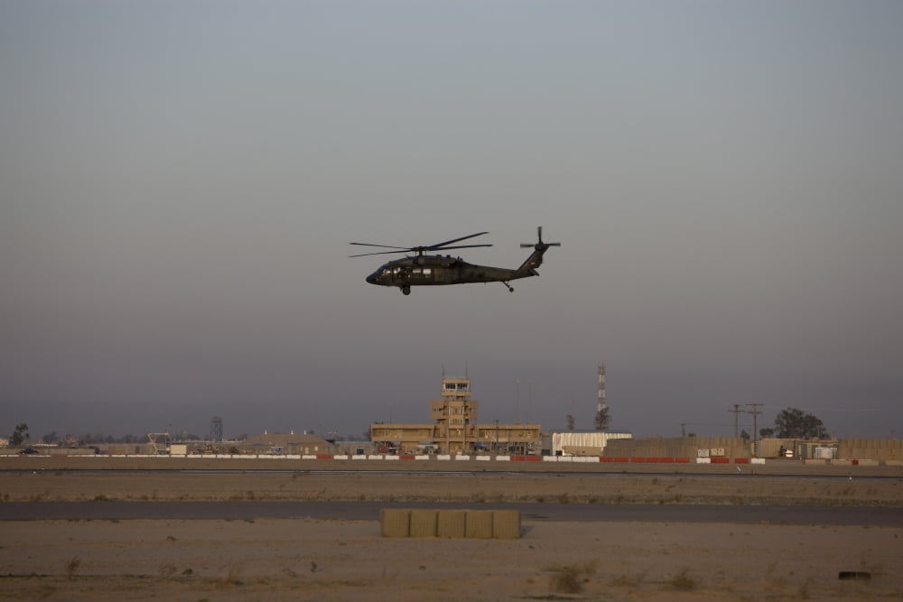 A UH-60 Blackhawk helicopter flies past the tower on Camp Speicher Canvas Art - Terry MooreStocktrek Images (35 x 23)
