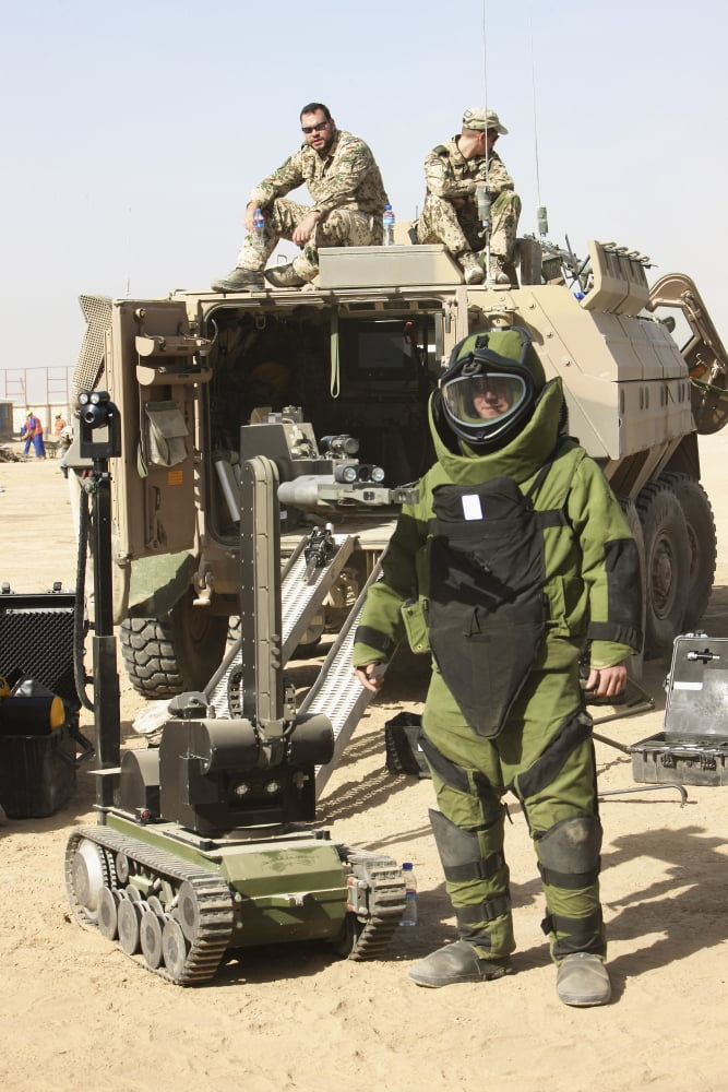 A US Marine dressed in a bomb suit stands next to a bomb disposal robot Canvas Art - Terry MooreStocktrek Images (24 x 35)