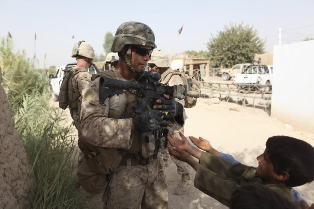 A US Marine gives a piece of candy to an Afghan boy during a patrol Canvas Art - Stocktrek Images (35 x 23)