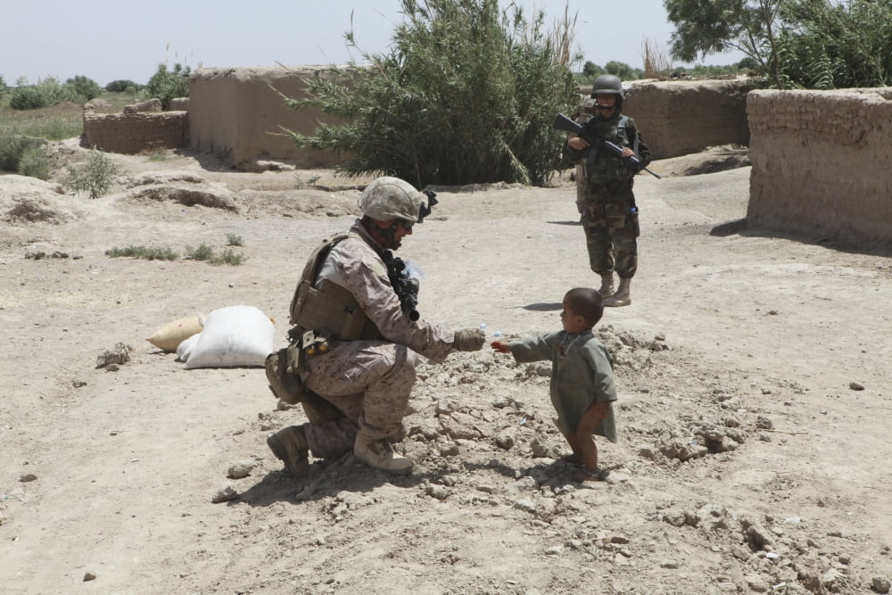 A US Marine gives candy to an Afghan child during a patrol in Marjah Afghanistan Canvas Art - Stocktrek Images (34 x 23)