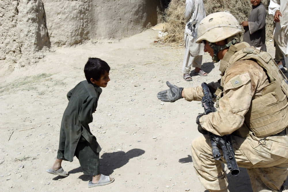 A US Marine holding out his hand to an Afghan boy in Helmand province Afghanistan Canvas Art - Stocktrek Images (34 x 23)