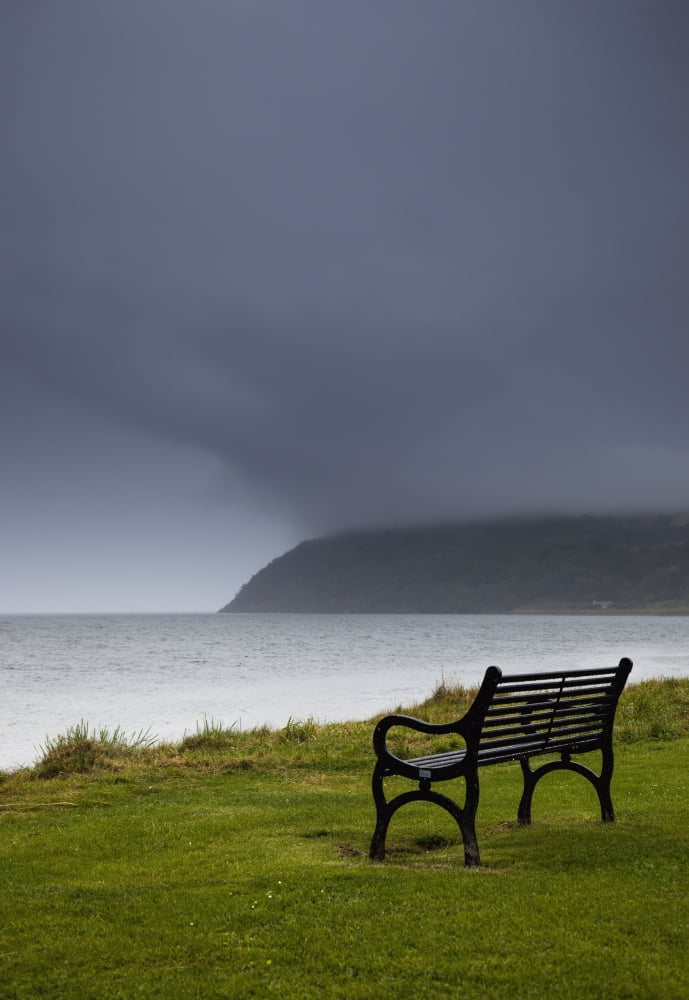 A bench at the waters edge with a dark stormy skyMoray firth scotland Canvas Art - John Short Design Pics (12 x 18)