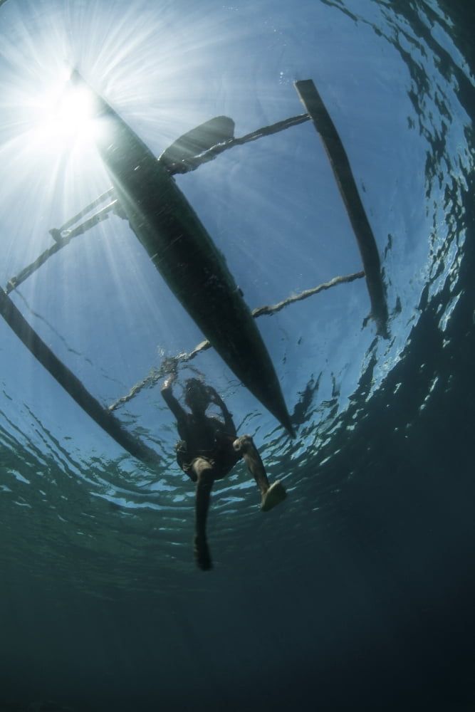 A fisherman uses a wooden outrigger near a remote island in Indonesia Canvas Art - Ethan DanielsStocktrek Images (23 x 34)