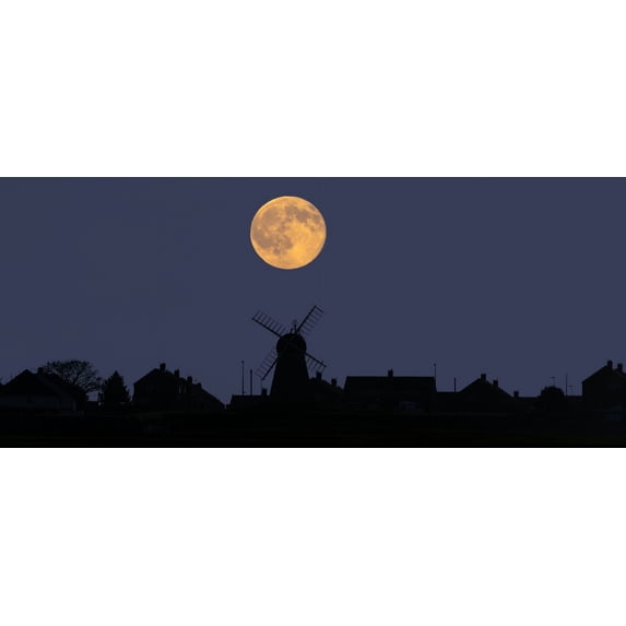 A glowing full harvest moon over the silhouette of a skyline of buildings; Whitburn, Tyne and Wear, England Poster Print by John Short / Design Pics (17 x 11)
