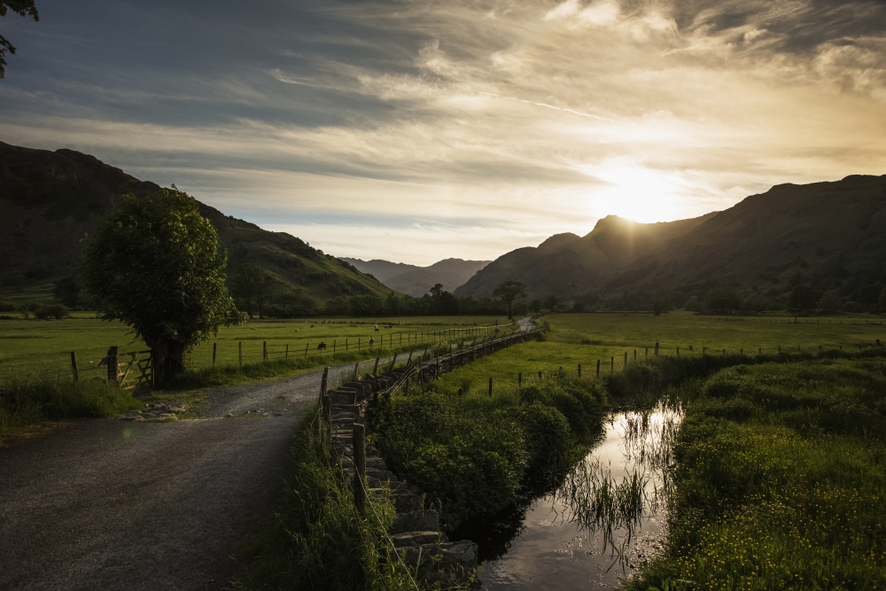 A gravel road between fields as the sun sets behind the mountains Lake District Cumbria England Canvas Art - John Short Design Pics (38 x 24)