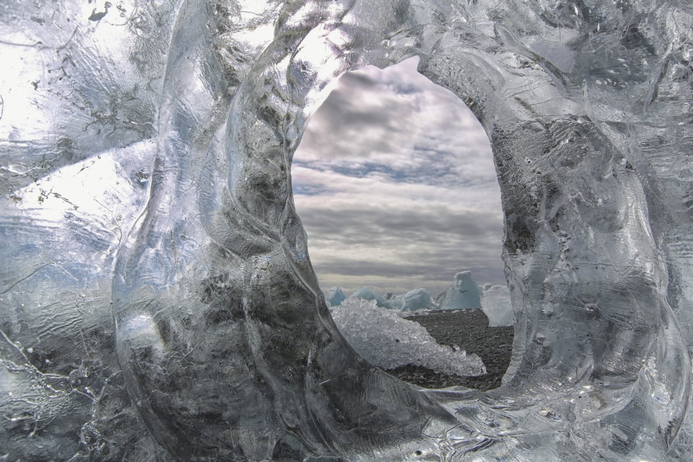 A hole in a coastal iceberg by the atlantic ocean with other icebergs seen through it iceland Canvas Art - Robert Postma Design Pics (38 x 24)
