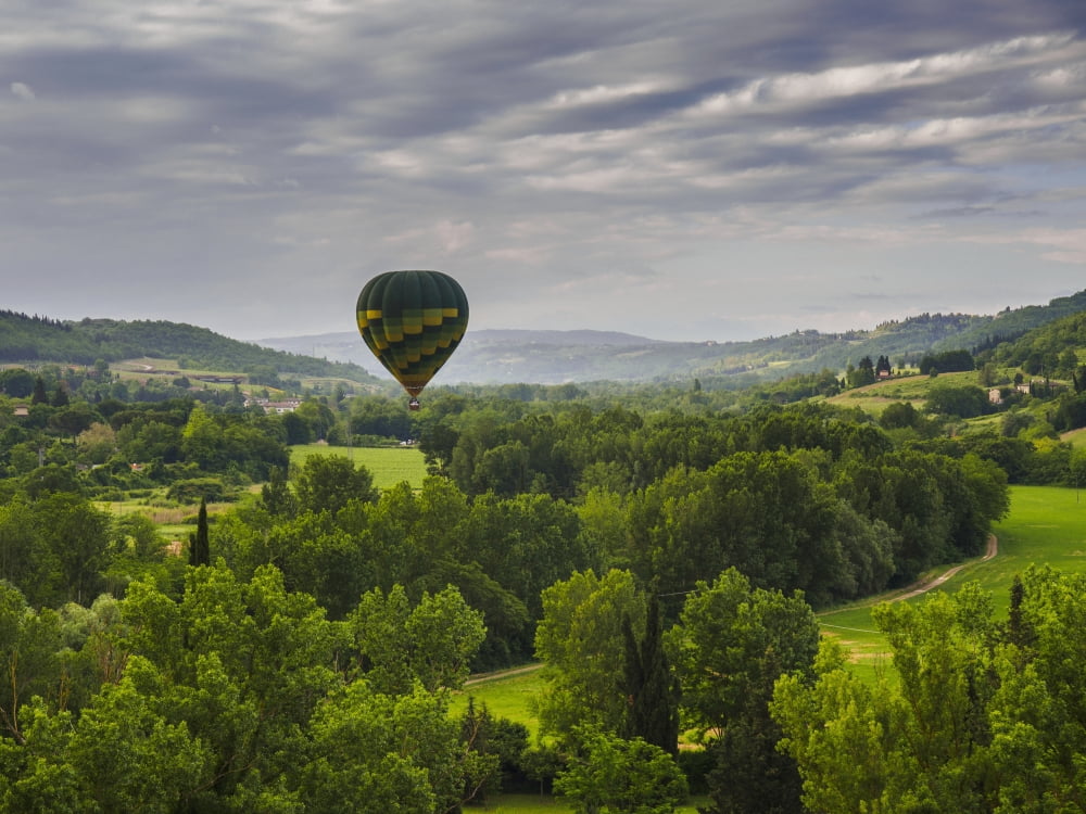 A hot air balloon flies low over a spring valley landscape Tuscany Italy Canvas Art - Brian Guzzetti Design Pics (17 x 13)