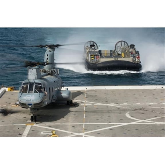 A hovercraft approaches USS  Orleans as a CH-46E Sea Knight sits on the flight deck Poster Print