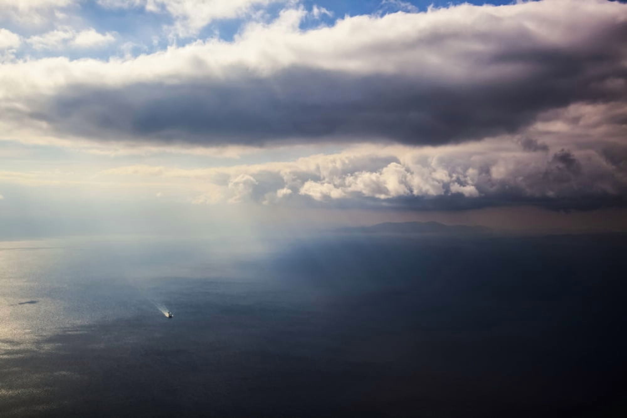 A lone boat on the Aegean sea under a cloudy sky and distant view of the coastline Greece Canvas Art - Reynold Mainse Design Pics (38 x 24)