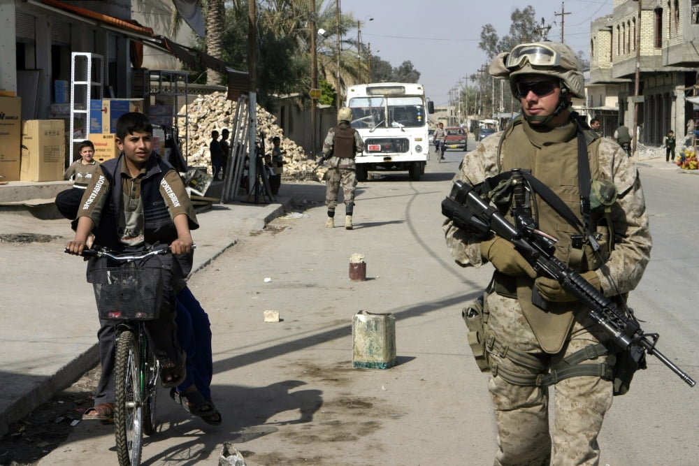 A machine gunner walks alongside an Iraqi boy on a bicycle Canvas Art - Stocktrek Images (34 x 23)