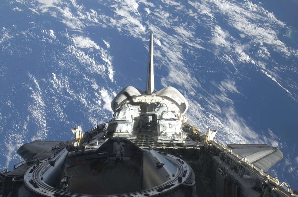 A partial view of Space Shuttle Atlantis backdropped by a blue and white Earth Canvas Art - Stocktrek Images (34 x 23)