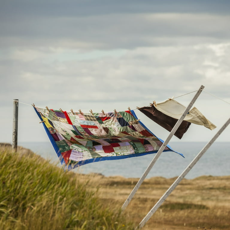 A patchwork blanket and pillow cases hanging on a clothesline with the  Atlantic ocean in the background; Newfoundland, Canada by Susan Dykstra /  Design Pics (30 x 30) 