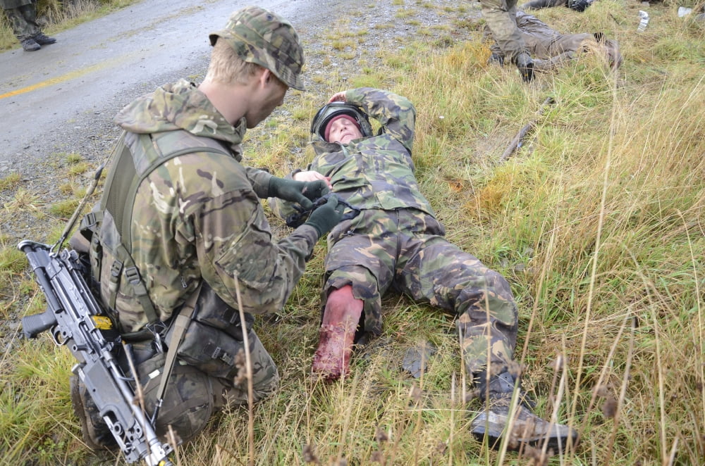 A patrol medic applies first aid to a simulated casualty Canvas Art - Andrew ChittockStocktrek Images (35 x 23)