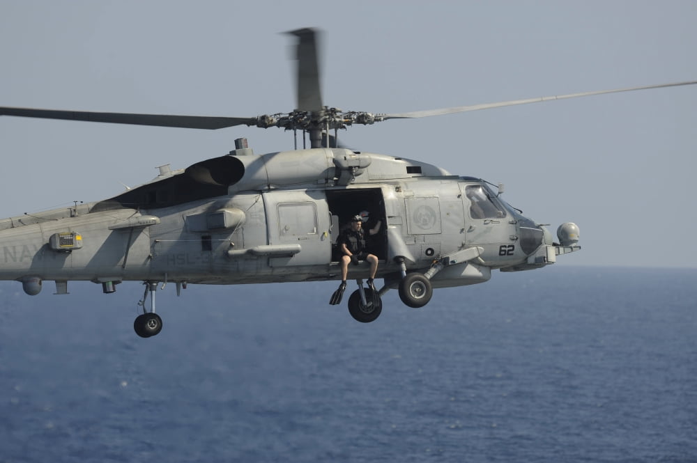 A rescue swimmer prepares to jump from an SH-60B Sea Hawk Canvas Art - Stocktrek Images (34 x 23)