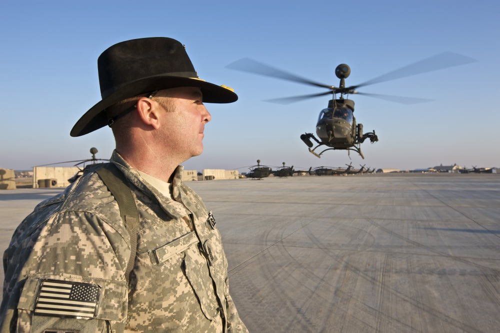 A soldier watches an OH-58D Kiowa as it prepares to land Canvas Art - Terry MooreStocktrek Images (35 x 23)