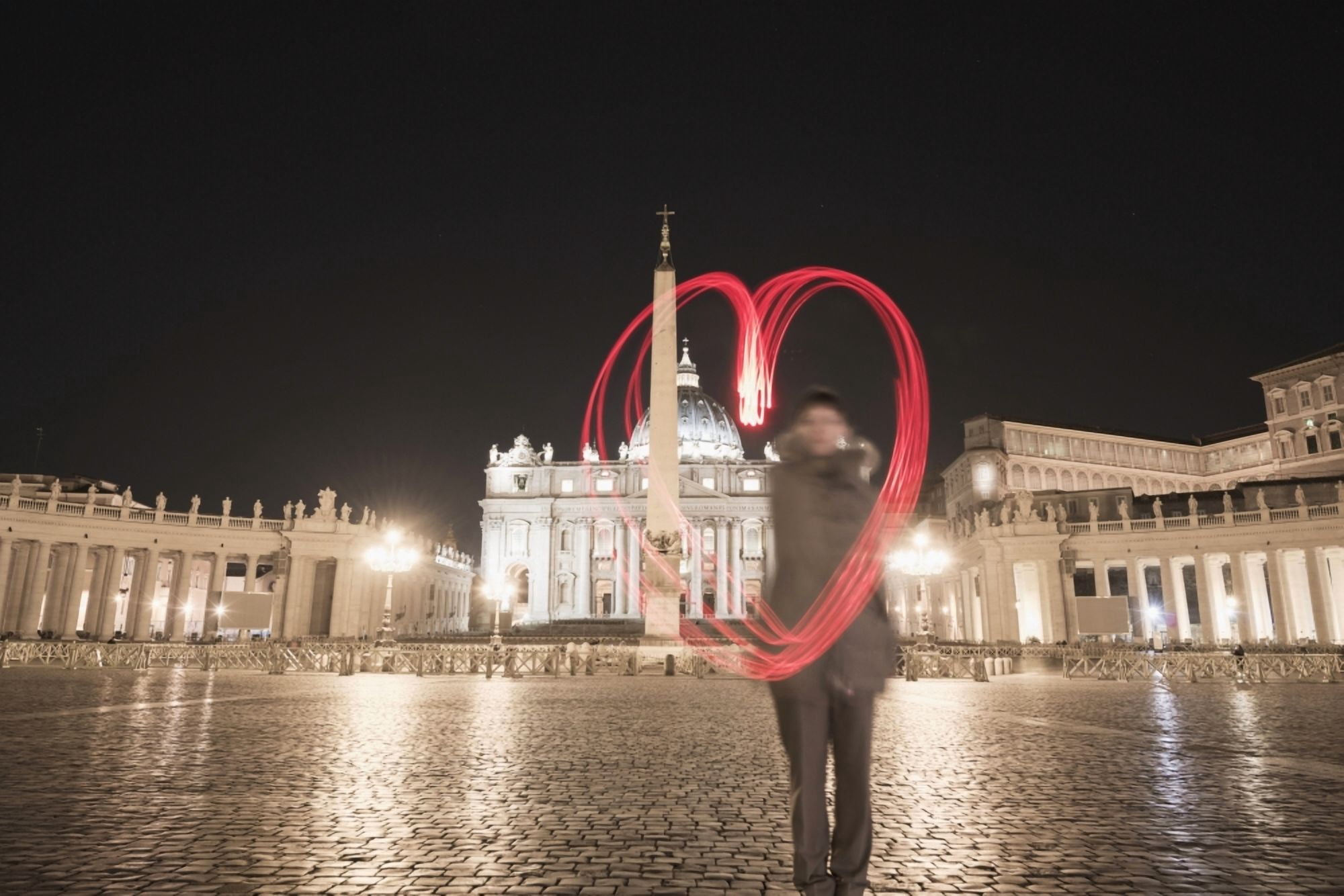 A woman stands with a red light trail in the shape of a heart in St Peters Square Rome Lazio Italy Canvas Art - Mats Silvan Design Pics (19 x 12)