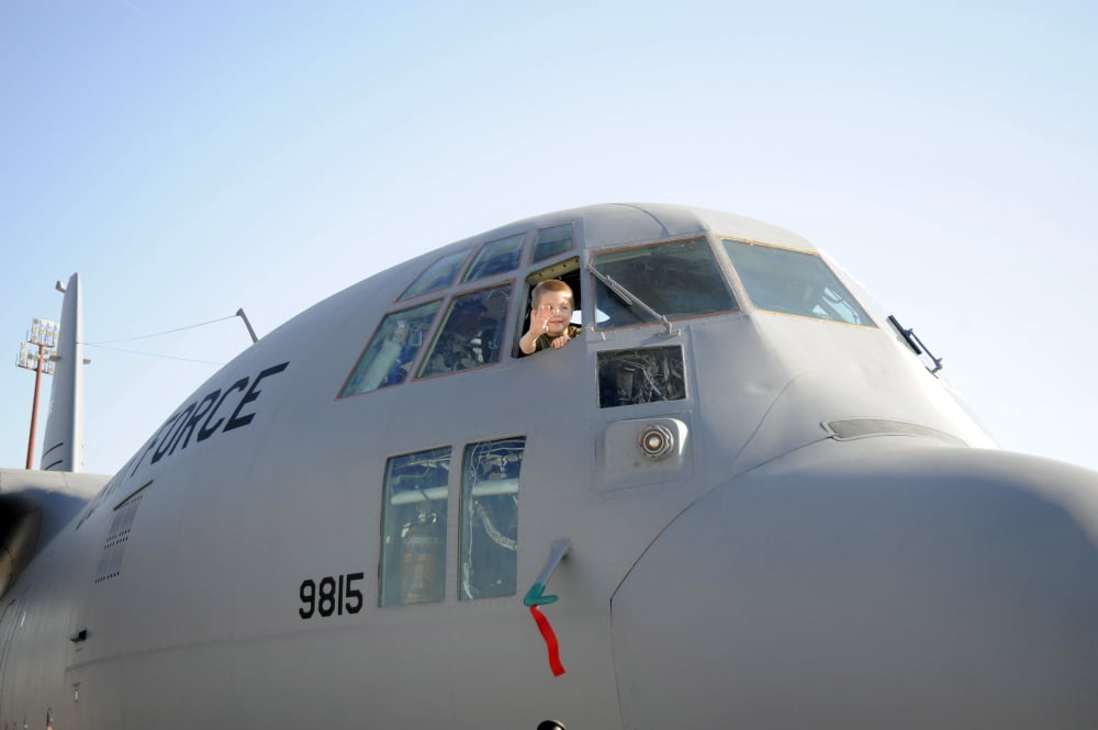 A young boy waves his hand out the cockpit window of a C-17 Globemaster III Canvas Art - Stocktrek Images (34 x 23)