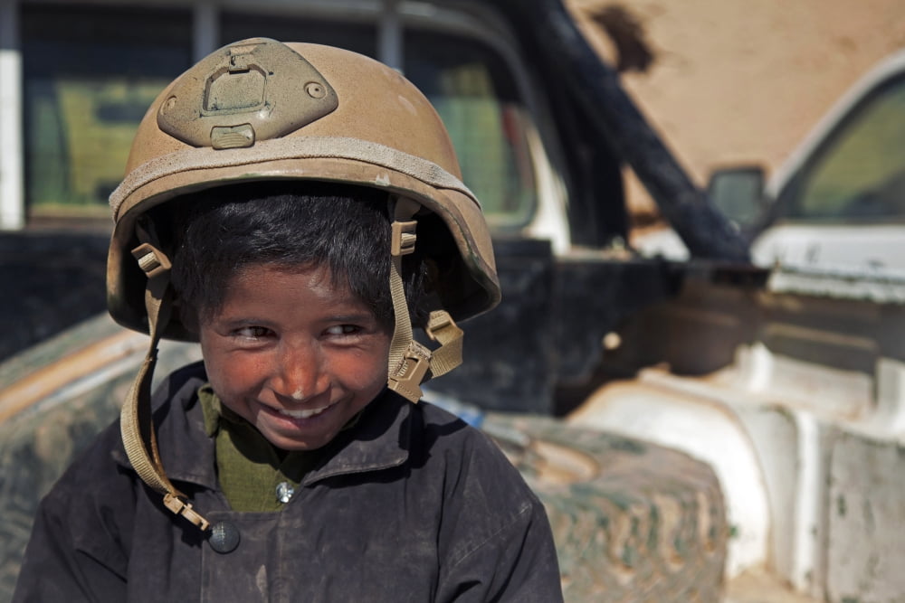 A young boy wears a coalition force members helmet in Afghanistan Canvas Art - Stocktrek Images (35 x 23)