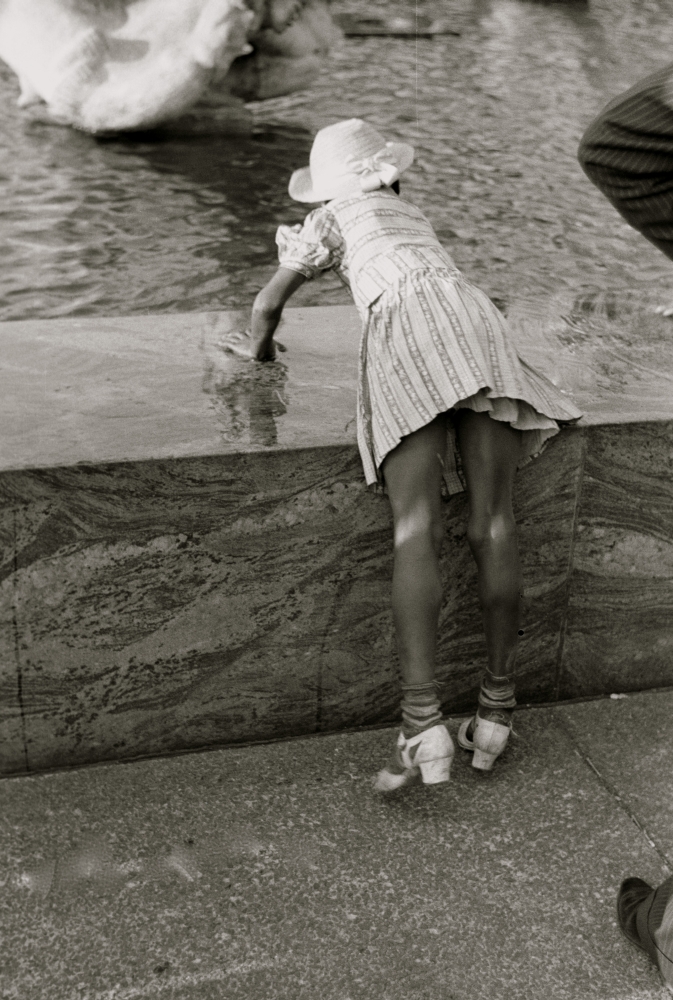 African American Girl leans over fountain pool to play with water Poster Print (18 x 24) - image 1 of 1