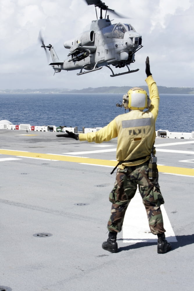 Airman directs an AH-1W Super Cobra onto the flight deck of USS Essex Canvas Art - Stocktrek Images (23 x 35)