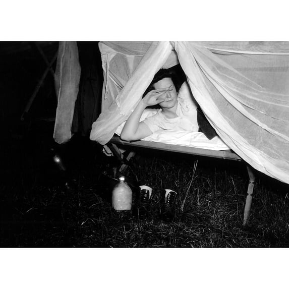 American Wac Raises The Netting Over Her Cot As A Photographer'S Flash Illuminates The Scene. On The Ground Are Her