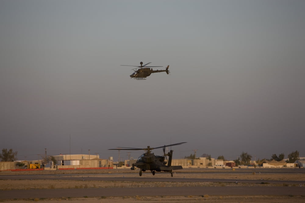 An AH-64D Apache Longbow Block III waits for an OH-58 Kiowa to clear his flight space Canvas Art - Terry MooreStocktrek Images (18 x 12)