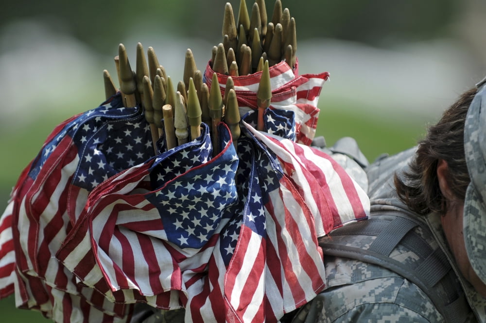 An Army soldiers backpack overflows with small American flags Canvas Art - Stocktrek Images (34 x 23)