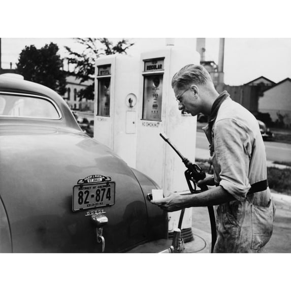 An Automobile Service Station Attendant Measures Out Gasoline In Accordance With The World War Ii Gasoline Rationing.