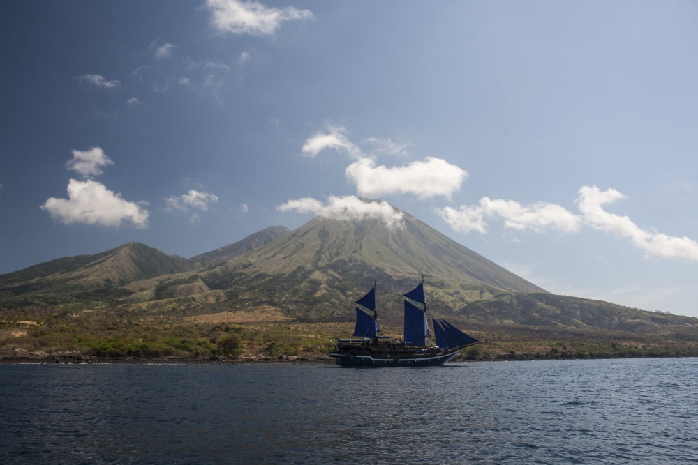An Indonesian pinisi schooner sails near a remote volcanic island Canvas Art - Ethan DanielsStocktrek Images (17 x 12)