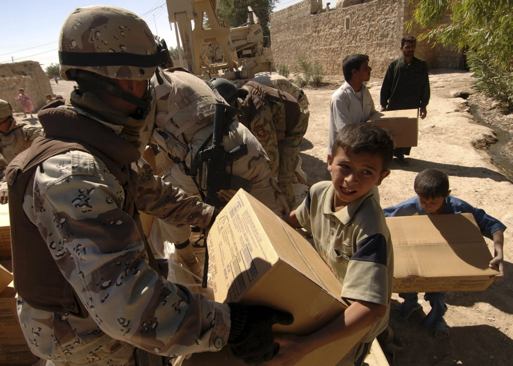 An Iraqi Army soldier handing a box of food to a boy of the Choloq tribe in Um Shababit Iraq Canvas Art - Stocktrek Images (34 x 24)