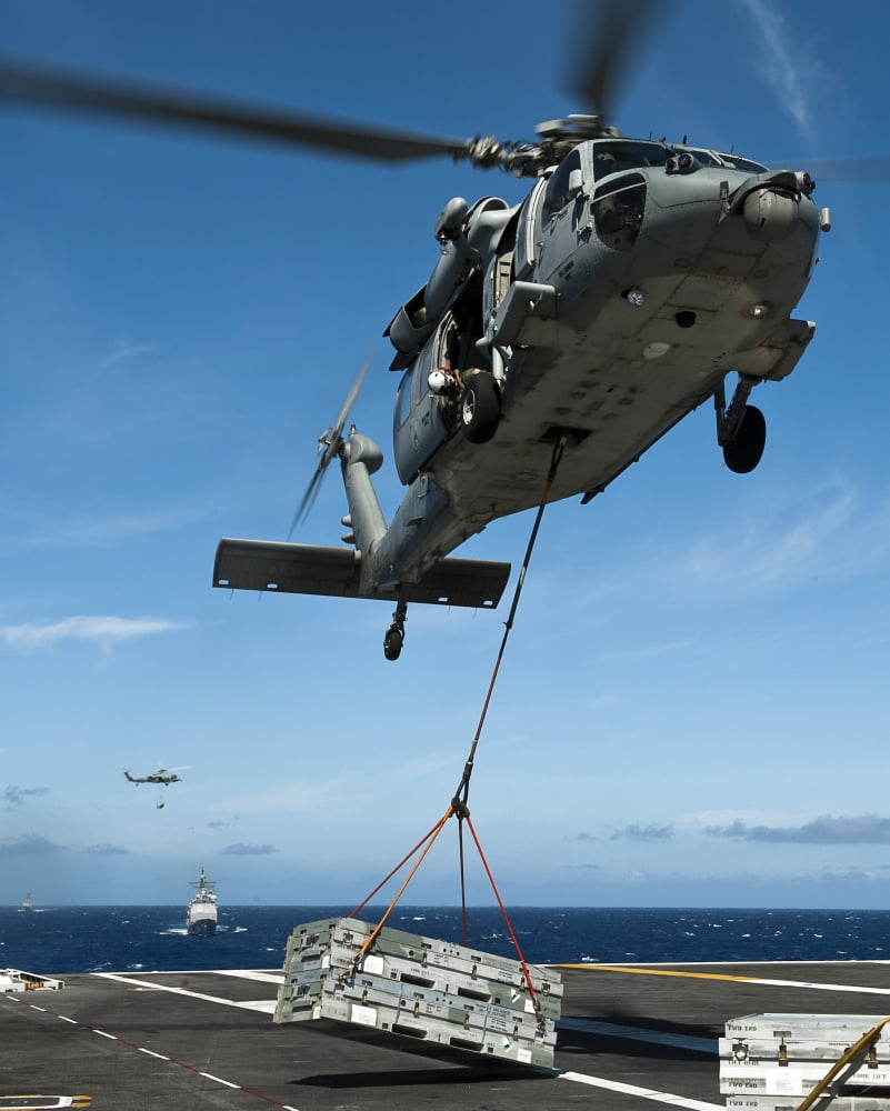 An MH-60S Sea Hawk helicopter lowers cargo onto the deck of USS John C Stennis Canvas Art - Stocktrek Images (26 x 32)
