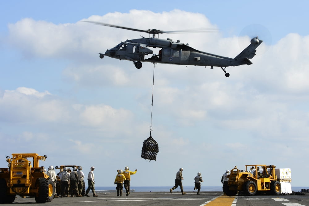 An MH-60S Sea Hawk helicopter lowers pallets of supplies onto USS Bonhomme Richard Canvas Art - Stocktrek Images (35 x 23)