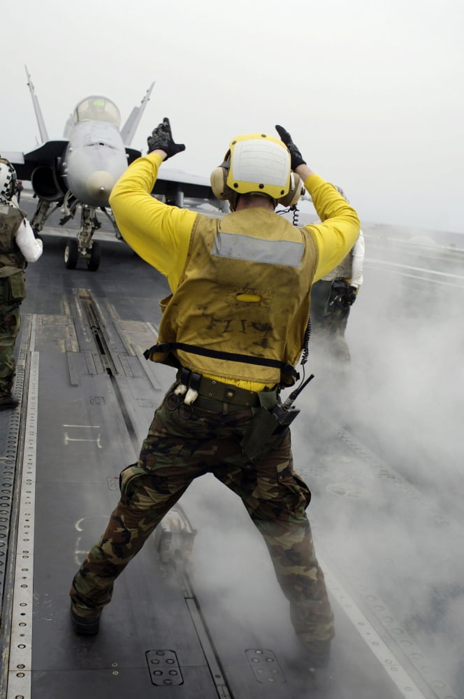 An aircraft director signals a FA-18C Hornet on the flight deck of USS Kitty Hawk Canvas Art - Stocktrek Images (23 x 34)