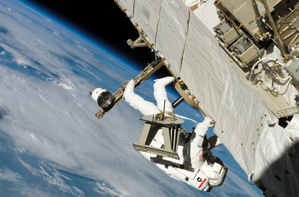 An astronaut crawls along a truss on the International Space Station Canvas Art - Stocktrek Images (34 x 23)