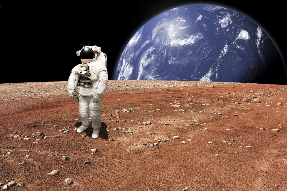 An astronaut standing on a barren world with planet rising in background Canvas Art - Marc WardStocktrek Images (35 x 24)