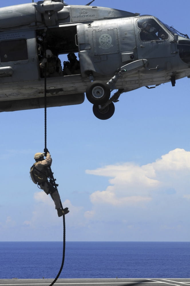 An explosive ordnance disposal technician fast ropes onto the flight deck of the USS Ronald Reagan Canvas Art - Stocktrek Images (23 x 34)