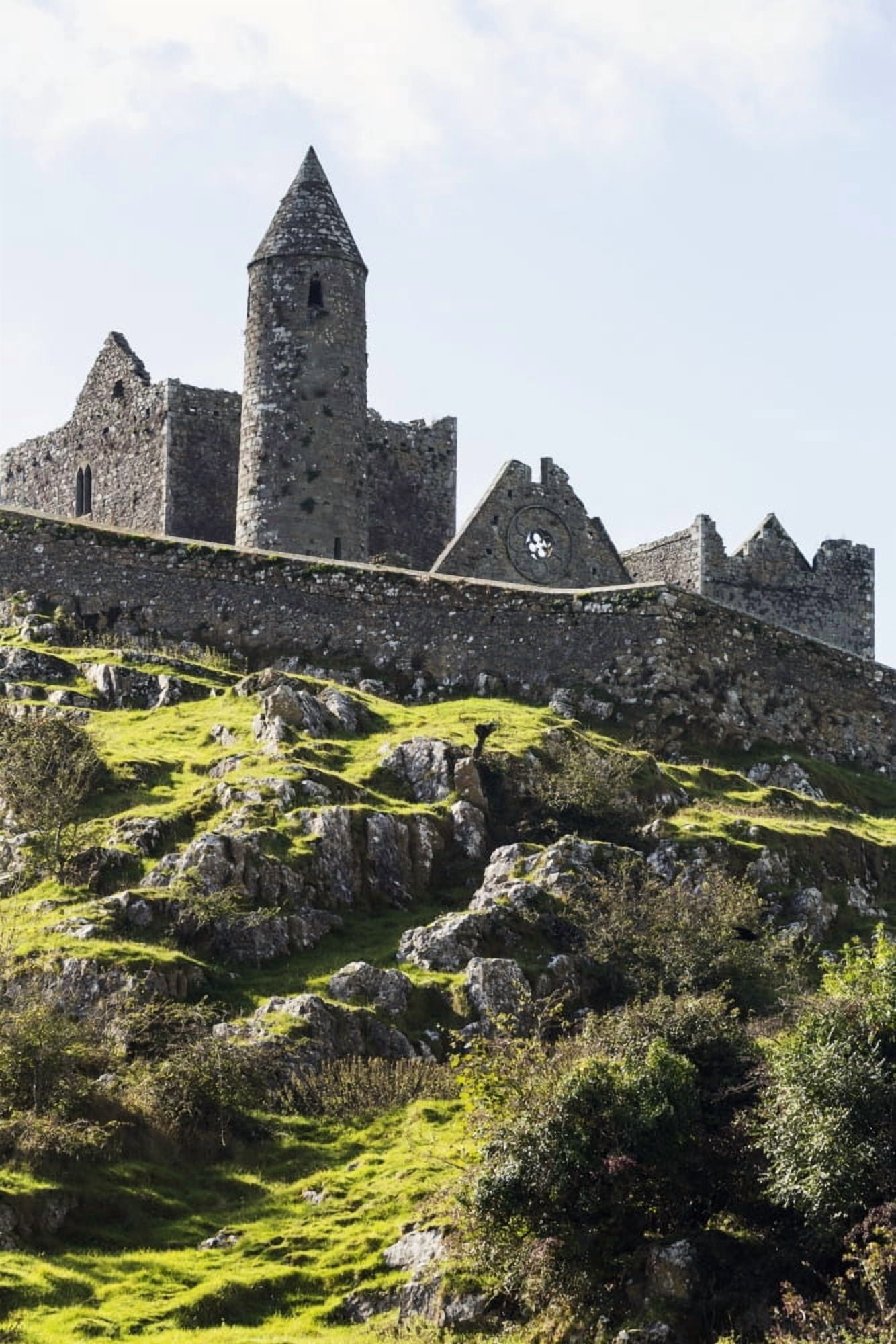 Ancient stone ruin with stone wall turret and church on rocky grassy hillside with blue sky and clouds Cashel County Tipperary Ireland Canvas Art - Michael Interisano Design Pics (12 x 19)