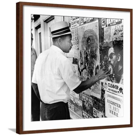 Art.com An African American Pokes His Finger into a Bullet Hole in the Oakland Black Panther's Headquarters Photo, Brown Frame Wall Art, 29" x 29"
