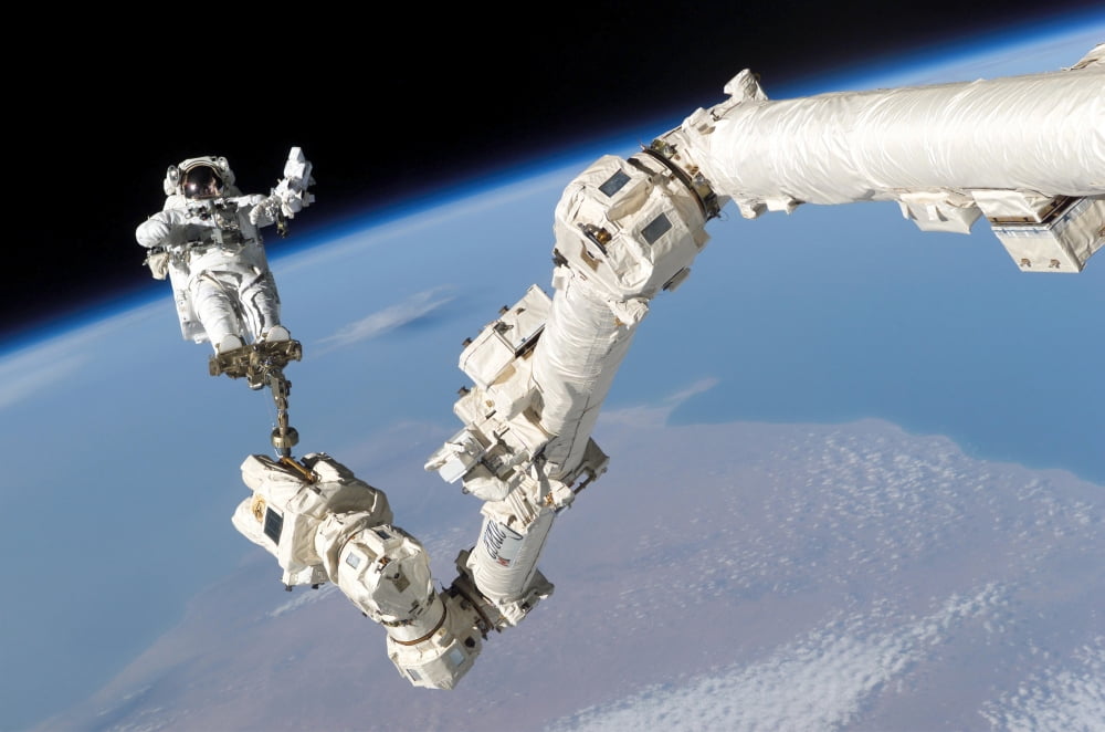 Astronaut anchored to a foot restraint on the International Space Stations Canadarm2 Canvas Art - Stocktrek Images (34 x 23)