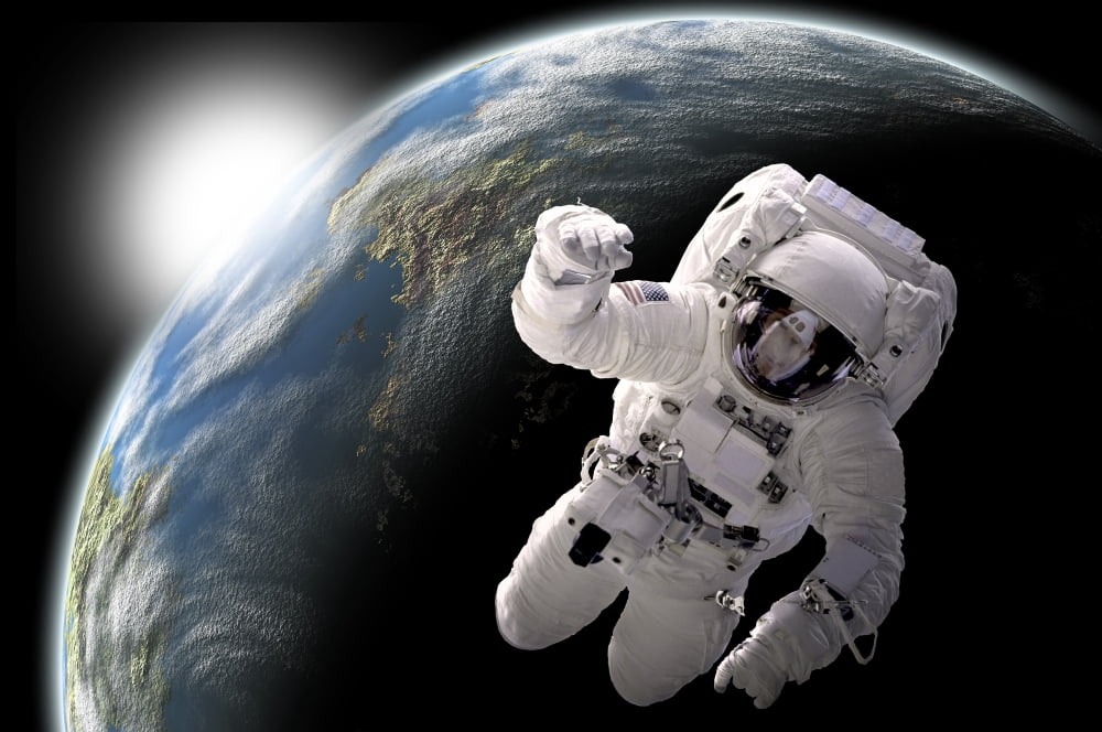 Astronaut floating in outer space with visible sunrise from an Earth-like planet Canvas Art - Marc WardStocktrek Images (17 x 12)
